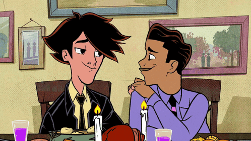 two men are sitting at a table with candles