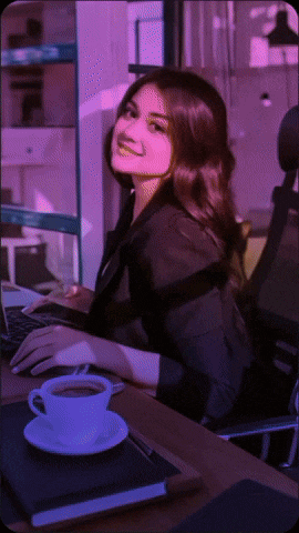 a woman sitting at a desk with a cup of coffee