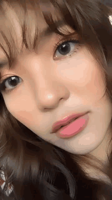 a close up of a woman 's face with a pink lip and gray eyes .