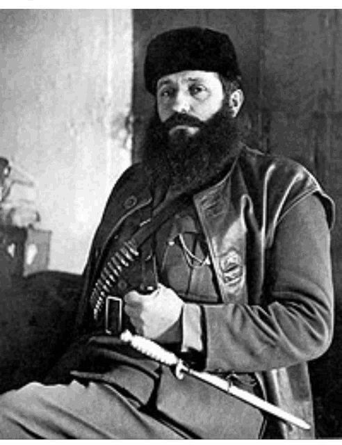 a man with a beard is holding a knife in a black and white photo .