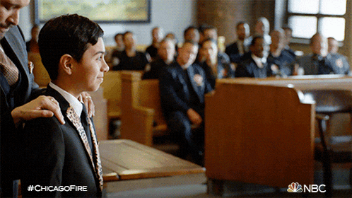 a man in a suit and tie is standing in front of a crowd with a nbc logo on the bottom