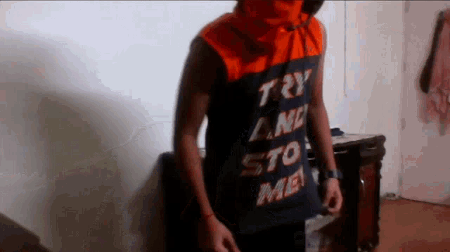a man wearing an orange and black shirt that says try a new sto me