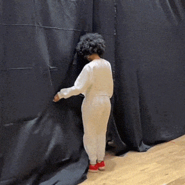 a person standing in front of a black curtain .