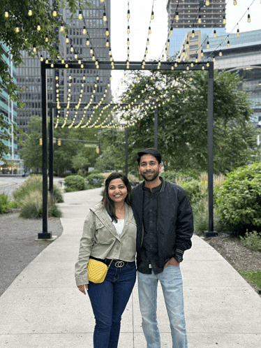 a man and a woman pose for a picture in front of a string of lights