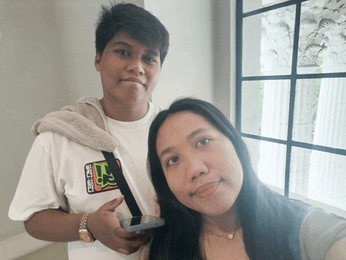 a man and a woman pose for a picture with the man wearing a white shirt that says ' a ' on the front