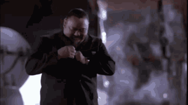 a man in a black jacket is standing in a room with smoke coming out of the ceiling .
