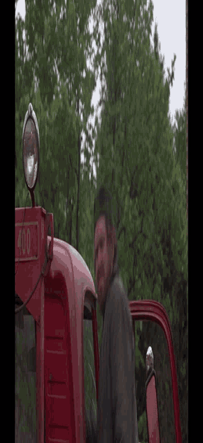a man is standing in front of a red tractor with the number 410 on it