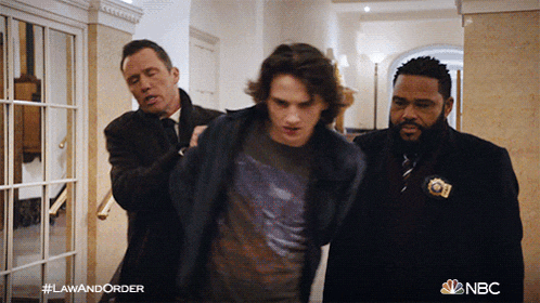 a man is being escorted by two men in a hallway with nbc written on the bottom