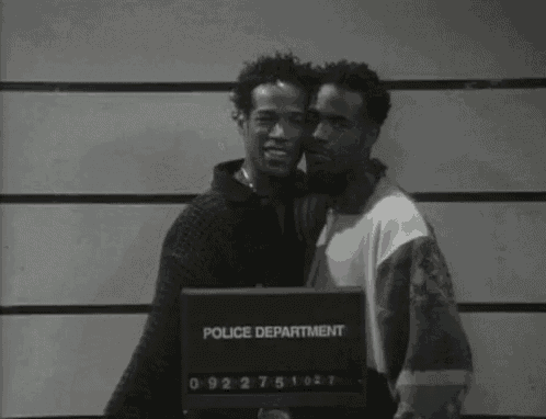 two men pose for a police department mugshot