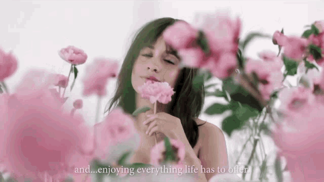 a woman is surrounded by pink flowers with the words " and enjoying everything life has to offer "