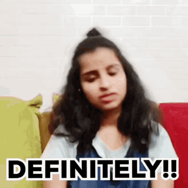 a girl is sitting on a couch and making a face with the words `` definitely '' written on her face .