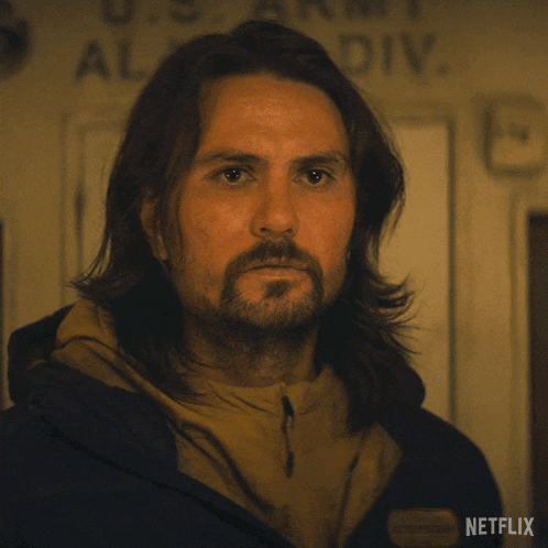 a man with long hair and a beard is wearing a jacket that says fine