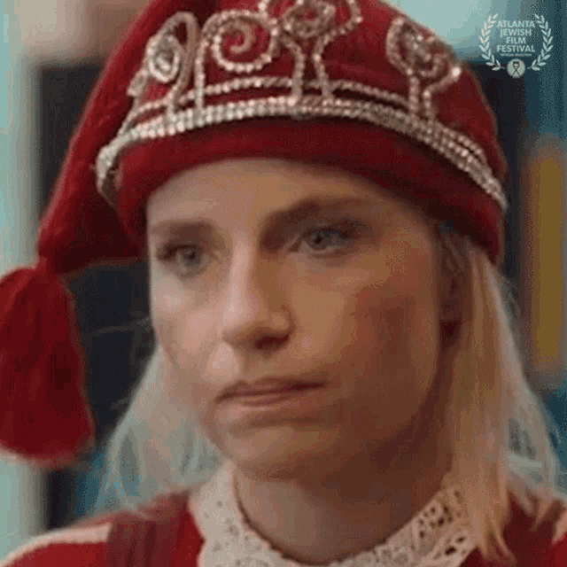 a woman wearing a red hat and a tiara is making a funny face .
