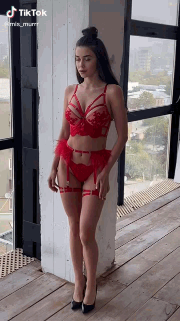 a woman in red lingerie is standing next to a window