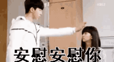 a man is putting his hand on a woman 's forehead in a room .