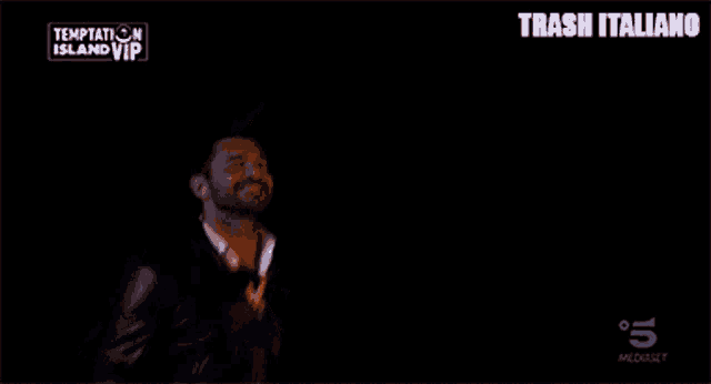 a man in a suit and bow tie is dancing in front of a screen that says trash italiano