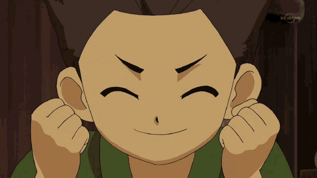 a boy in a green shirt is smiling in front of a tv screen that says tv japan