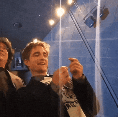 a man wearing a shirt that says ' harry potter ' on it stands next to another man