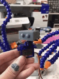 a person with a tattoo on their finger is holding a robot