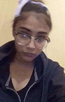 a woman wearing glasses and a headband is making a face