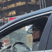 a woman is driving a car with a tiktok sticker on the steering wheel