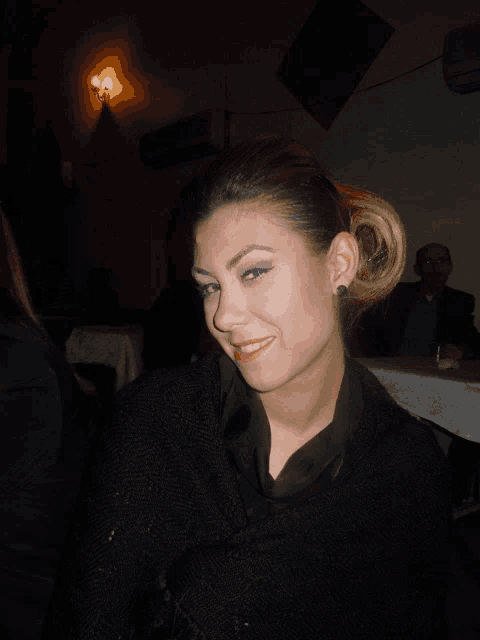 a woman wearing a black sweater and red lipstick smiles at the camera