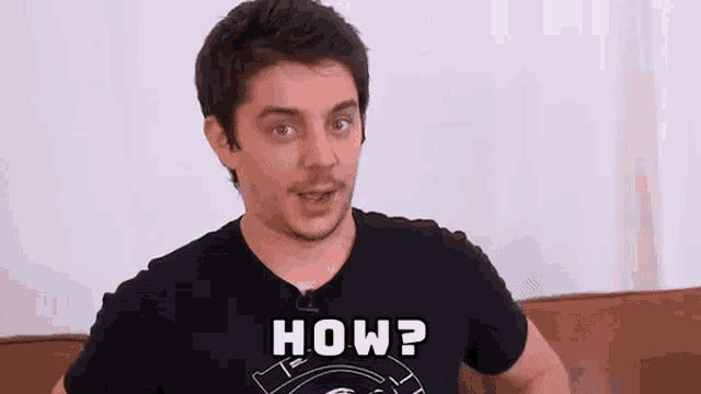 a man is sitting on a couch wearing a black shirt that says `` how ? '' .