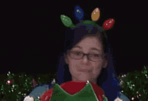 a woman giving a thumbs up wearing a headband with christmas lights on it
