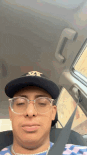 a man wearing a hat and glasses is sitting in a car