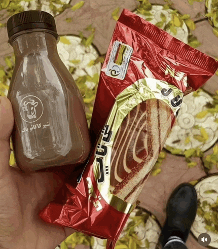a person is holding a bottle of chocolate milk next to a bag of cake