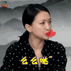 a woman with a red heart in her mouth is wearing a polka dot shirt .