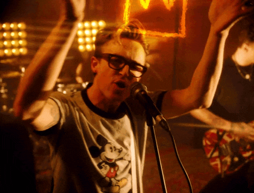a man singing into a microphone wearing a mickey mouse shirt
