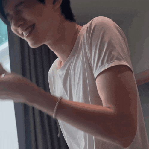 a man in a white shirt is smiling with his eyes closed and his arms outstretched