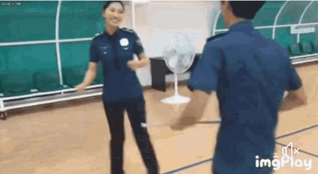 a man and a woman in police uniforms are dancing on a basketball court .