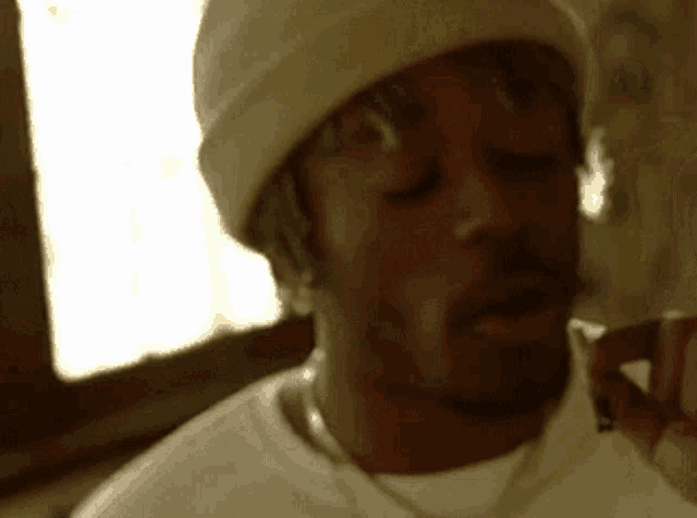 a close up of a man wearing a beanie and a white shirt