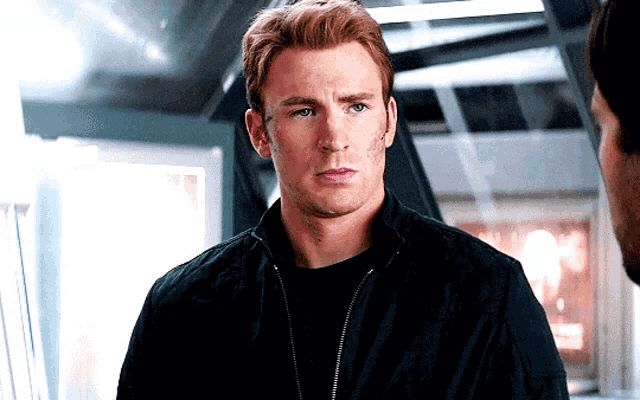 a man in a black jacket looks at another man
