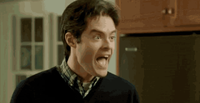 a man is making a funny face in front of a refrigerator .