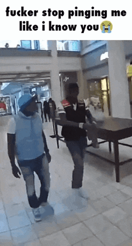 a man in a blue hat is walking with another man in a black vest .