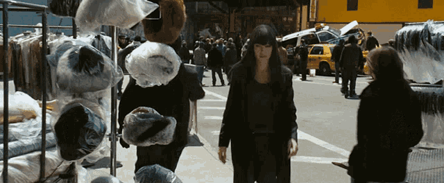 a woman in a black coat walks down a street in front of a yellow taxi cab that says ' a ' on the side