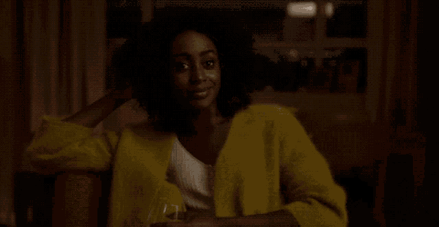 a woman in a yellow sweater is sitting in a chair with a glass of wine