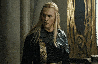 a man with long blonde hair is wearing a black and gold dress