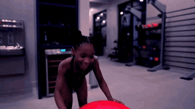 a woman is playing with a red ball in a dark room