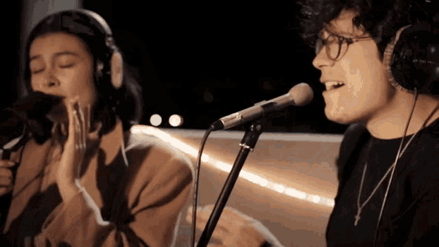a man and a woman are singing into microphones while wearing headphones