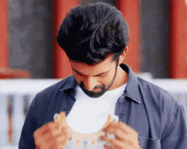 a man with a beard is eating a sandwich with french fries
