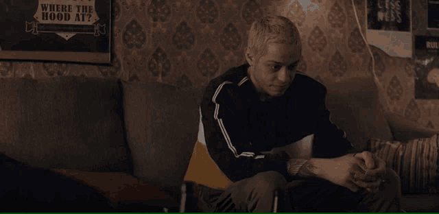 a man sits on a couch in front of a sign that says where the hood at