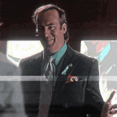 a man in a suit and tie is smiling and holding a phone