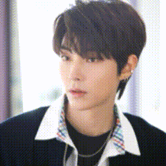 a close up of a young man wearing a black shirt and a plaid collar .