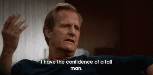 a man in a blue shirt is saying i have the confidence of a tall man