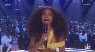 a woman in a yellow top is speaking into a microphone on a stage
