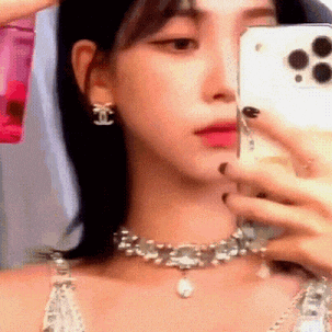 a woman is taking a selfie in front of a mirror while wearing a choker and earrings .